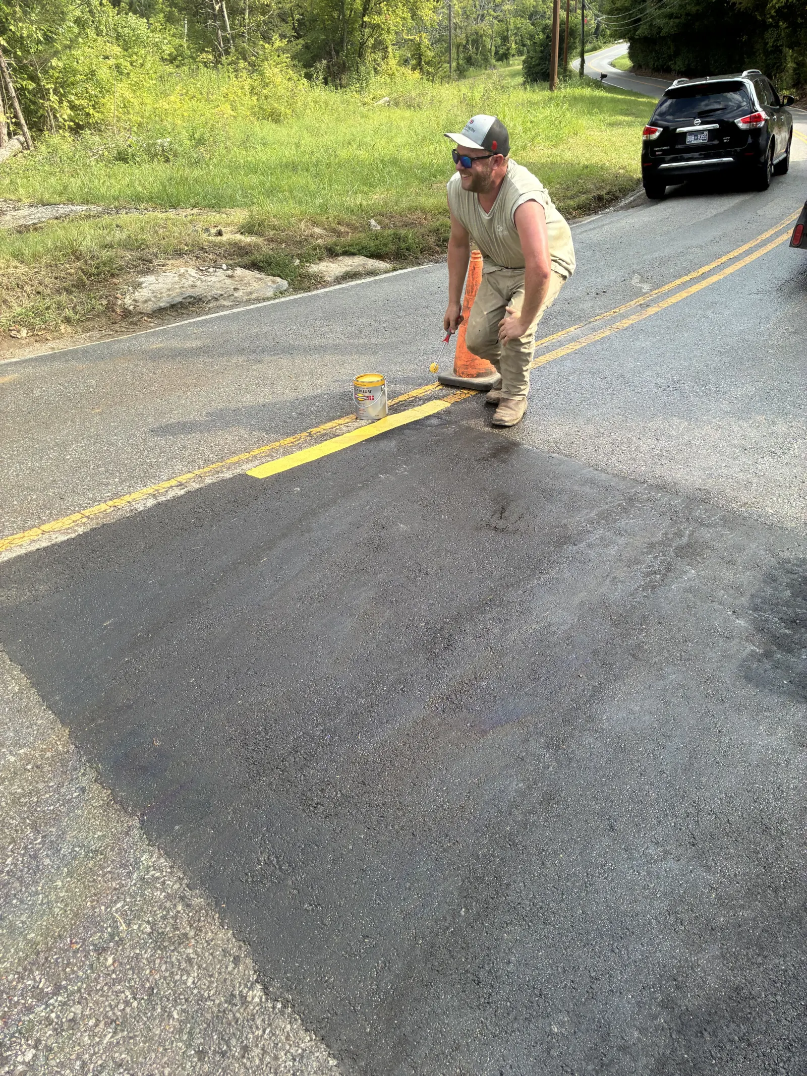 Fresh asphalt being finished over a sewer line road crossing