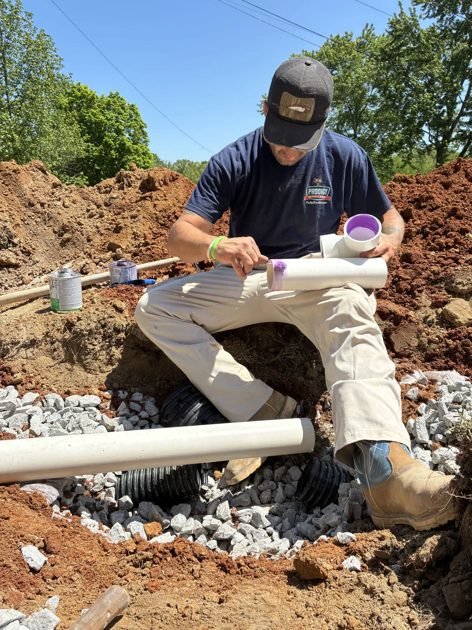 Technician assembling drain field pipe beside the gravel trench