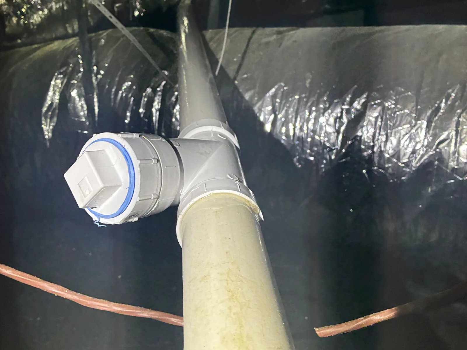 New cleanout tee and plug on a drain line in a crawl space