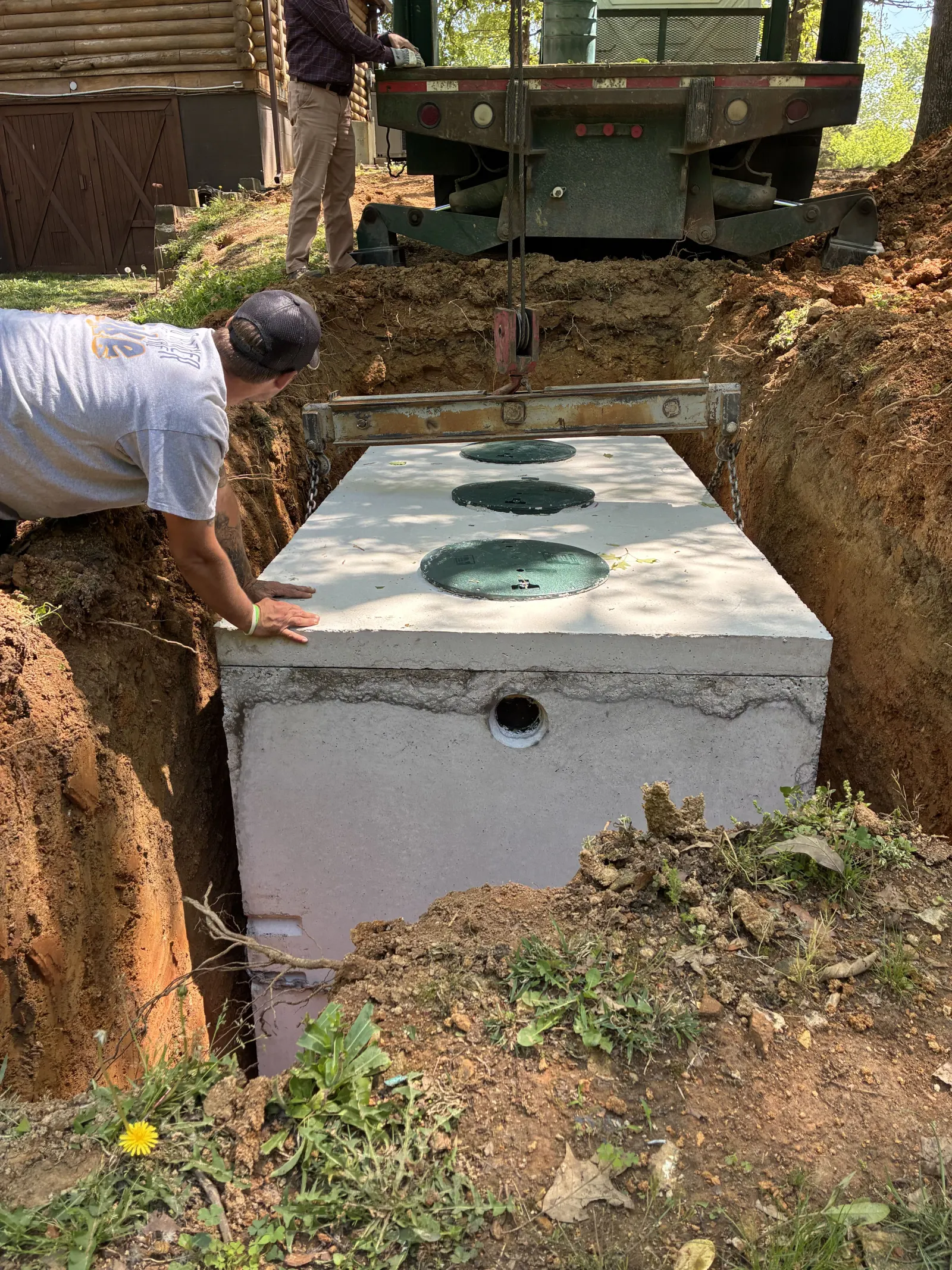 Precast concrete septic tank lowered into the excavation from a boom truck