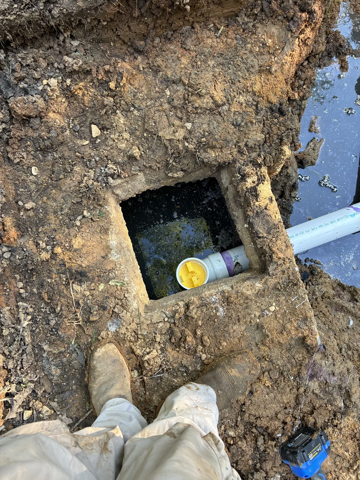 Capped inlet pipe seen through the open access hole of a septic tank