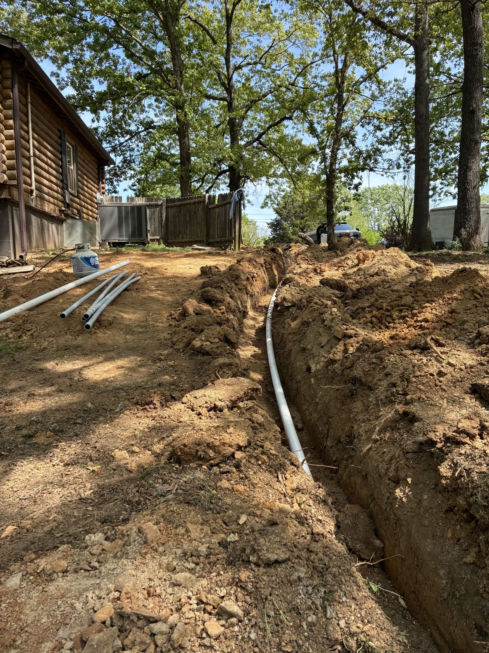 Trench with new pipe running toward a house