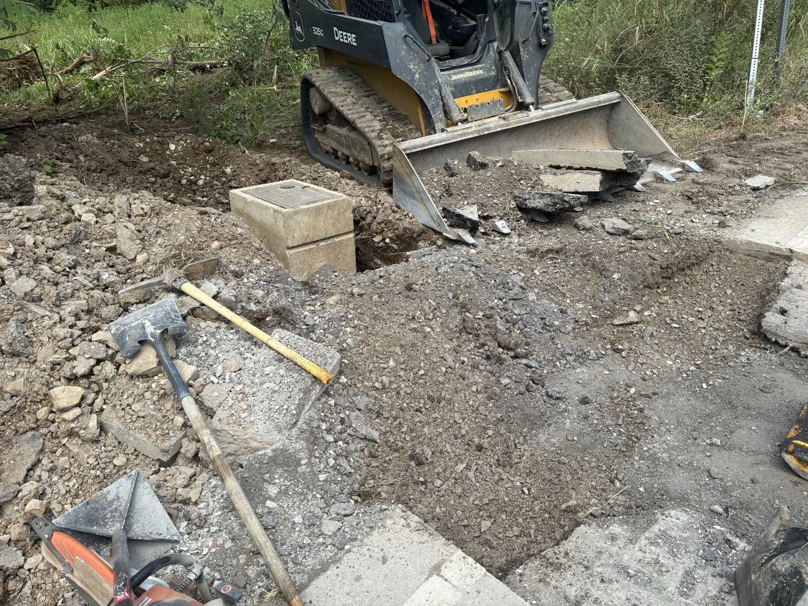Track loader opening the pavement for a sewer line crossing